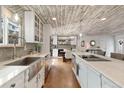 A kitchen with white cabinets, a farm sink, stainless steel appliances, a large island with barstool seating at 11542 W 67Th Way, Arvada, CO 80004