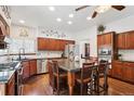 Gourmet kitchen with wood cabinetry, stainless steel appliances, granite countertops, and a large central island at 7804 Silverweed Way, Lone Tree, CO 80124