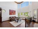 Bright living room with soaring ceilings, large windows, wood floors, and a striking artistic accent wall at 7804 Silverweed Way, Lone Tree, CO 80124
