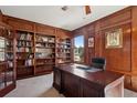 Wood paneled office space with built-in bookshelves, a large executive desk, and natural light at 7804 Silverweed Way, Lone Tree, CO 80124