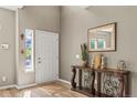 A foyer with light wood floors and a decorative console table topped with a mirror at 15021 Josephine St, Thornton, CO 80602