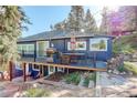 Exterior view of the blue home's deck area with table, grill, and natural surroundings at 4642 Plettner Ln, Evergreen, CO 80439