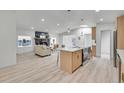 Open-concept living room with modern kitchen island, a stone fireplace, and neutral furniture on wood floors at 328 Quay St, Lakewood, CO 80226