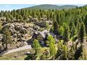 Aerial view of a log home nestled in a picturesque forest with surrounding rock outcroppings at 6150 Bluebell Ln, Evergreen, CO 80439