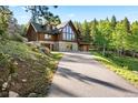 Stunning log home features a stone foundation, attached garage, and natural landscaping at 6150 Bluebell Ln, Evergreen, CO 80439