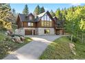 Stunning log home features a stone foundation, attached garage, and natural landscaping at 6150 Bluebell Ln, Evergreen, CO 80439