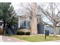 Gray two-story home with brick chimney and landscaped front yard with 'For Sale' sign at 4243 Flanders St, Denver, CO 80249