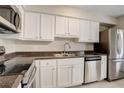 A lovely kitchen featuring stainless steel appliances, white cabinets, and dark countertops with a double basin sink at 7165 S Gaylord St # E09, Centennial, CO 80122