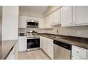 A lovely kitchen with stainless steel appliances, white cabinets, and dark countertops with a double basin sink at 7165 S Gaylord St # E09, Centennial, CO 80122