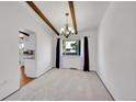 Dining room featuring exposed beam ceiling, chandelier, neutral carpet and view to kitchen at 3792 S Fenton Way, Denver, CO 80235