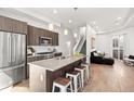 Open kitchen view showcasing stainless appliances, island with seating, and hardwood floors at 2321 Eliot St, Denver, CO 80211