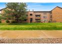 Apartment complex with beautiful mature trees, grass, and a charming brick and wood facade at 201 Wright St # 106, Lakewood, CO 80228