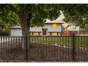 Lovely home with a well-kept lawn, black iron fence, and mature landscaping at 13055 E Dakota Ave, Aurora, CO 80012