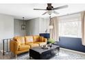 A modern living room features a stylish ceiling fan, a brown leather couch, and a blue patterned rug at 13055 E Dakota Ave, Aurora, CO 80012