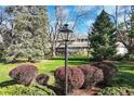 Street sign in beautiful landscaped front yard with mature trees and a charming two story home in background at 4 Brookside Dr, Greenwood Village, CO 80121
