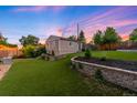 Spacious backyard with lush green lawn, retaining walls, and a detached structure perfect for recreation or storage at 5125 Umatilla St, Denver, CO 80221