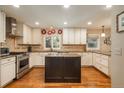 Well-equipped kitchen with stainless steel appliances, granite countertops, and custom cabinets, centered by an island at 7076 S Niagara Ct, Centennial, CO 80112