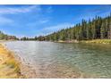 Picturesque view of a calm lake surrounded by lush green trees and clear blue skies at 609 Brook Dr, Idaho Springs, CO 80452