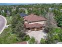 Aerial view of a home surrounded by dense trees, featuring a two-car garage and well-kept lawn at 8707 Windhaven Dr, Parker, CO 80134