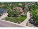 Beautiful aerial view of a tan two-story home surrounded by lush trees and a well-manicured lawn at 8707 Windhaven Dr, Parker, CO 80134