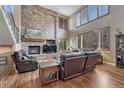 Cozy living room with stone fireplace, large windows, and hardwood floors provides an inviting atmosphere at 8707 Windhaven Dr, Parker, CO 80134