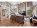 Open living room features a stone fireplace, high ceilings, hardwood floors, and a staircase at 8707 Windhaven Dr, Parker, CO 80134