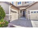 A side view of a home with stone accents and a two-car garage and large entry door with sidelight at 10375 Knollside Dr, Parker, CO 80134
