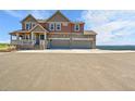 Beautiful two-story home with a covered porch and spacious driveway on a sunny day at 49346 E County Road 6, Bennett, CO 80102
