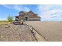 Inviting two-story home with covered porch, three-car garage, and landscaped front yard at 49346 E County Road 6, Bennett, CO 80102