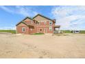 Exterior view of a two-story home, showcasing a covered porch and spacious outdoor area at 49346 E County Road 6, Bennett, CO 80102