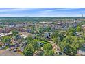 An aerial view shows mature trees, a home with a manicured lawn, and a cityscape in the distance at 5614 Yarrow St, Arvada, CO 80002