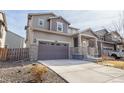 Beautiful two-story home has a two-car garage, gray siding, stone accents, and manicured front yard at 10962 Vaughn St, Commerce City, CO 80022