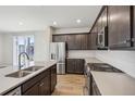 Modern kitchen with stainless steel appliances, dark wood cabinets, and light countertops at 21185 E 62Nd Ave, Aurora, CO 80019