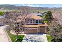 Aerial view of a two-story house with a well-maintained lawn, a three car garage, and mountain views at 8487 S Nelson St, Littleton, CO 80127