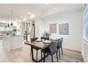 Contemporary dining area features a wooden table, modern lighting, and seamless flow to the kitchen at 15276 W 69Th Pl, Arvada, CO 80007