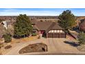 Lovely home highlighting a brick facade, a red front door, mature trees, and a three-car garage at 12007 W 54Th Dr, Arvada, CO 80002