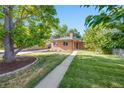 Charming brick home boasts a lush lawn, mature trees, and inviting walkway at 4850 E Dartmouth Ave, Denver, CO 80222