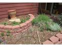 Close up of professionally landscaped front yard with brick border, mature plants and mulch at 13168 W 62Nd Dr, Arvada, CO 80004