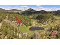Scenic aerial view of the property with mountain views, a large pond, and lush forest surroundings, perfect for relaxation at 22025 Oehlmann Park Rd, Conifer, CO 80433