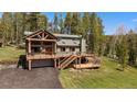 Charming home boasting a large deck perfect for outdoor gatherings and a two-car garage, surrounded by mature trees at 22025 Oehlmann Park Rd, Conifer, CO 80433