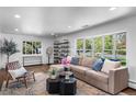 Bright and airy living room featuring a cozy sectional sofa, modern shelving, and large windows at 5020 W Quarles Dr, Littleton, CO 80128