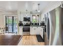 Bright kitchen boasts stainless steel appliances, white cabinets, modern backsplash, and hardwood floors at 6160 Taft Ct, Arvada, CO 80004