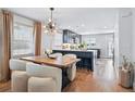 Bright kitchen and dining area with hardwood floors, modern light fixture, and black kitchen island at 796 Ivanhoe St, Denver, CO 80220