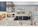 Modern kitchen with marble countertops, sleek dark cabinetry, stainless steel appliances, and herringbone backsplash at 796 Ivanhoe St, Denver, CO 80220