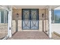 Front entrance with black iron security door and brick walkway at 3257 S Pontiac St, Denver, CO 80224