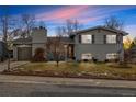 Charming two-story home with a gray brick exterior, a well-maintained lawn, and a lovely front yard at dusk at 6864 Balsam St, Arvada, CO 80004