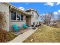 Inviting front porch with cozy seating and a well-manicured lawn leading up to a charming gray brick home at 6864 Balsam St, Arvada, CO 80004