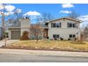 Charming two-story home with a well-maintained lawn and mature trees under a clear sky at 6864 Balsam St, Arvada, CO 80004