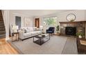 Staged living room with hardwood floors, a fireplace, and a large window that offers natural light at 6864 Balsam St, Arvada, CO 80004