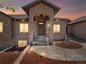 Charming stone-accented home entrance featuring a covered porch, a wood door, and manicured landscaping at 1505 Castlecombe Ln, Monument, CO 80132